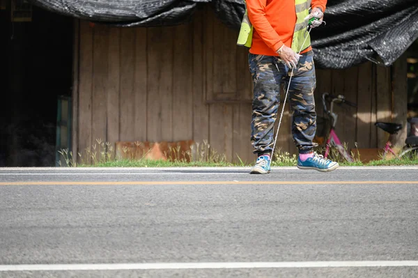 Trabajador vistiendo uniforme está rayando con la medición en la carretera —  Fotos de Stock