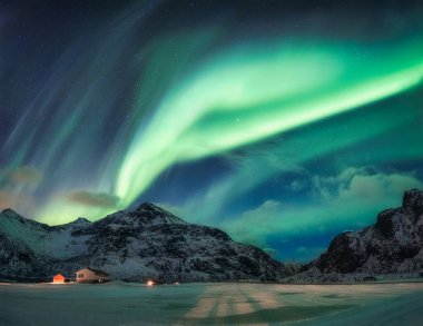 Aurora Borealis ya da Kuzey Işıkları Norveç 'in Lofoten adalarındaki Flakstad' daki Arktik Daire 'deki karlı dağların üzerinden geçer.