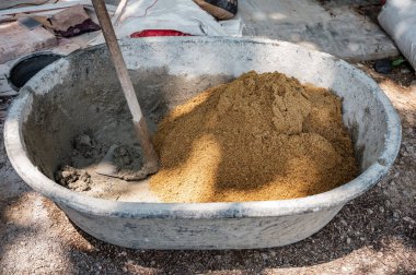 İnşaat için çimento, kum ve suyu kovada çapalamak