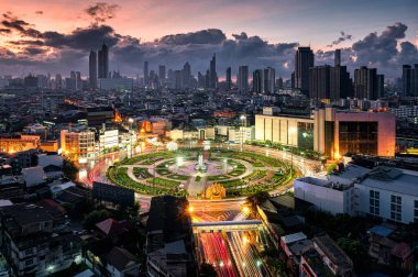 Bangkok, Tayland 'daki Wongwianyai kavşağının üzerinde araba trafiği ve gökdelenli bir anıt var.