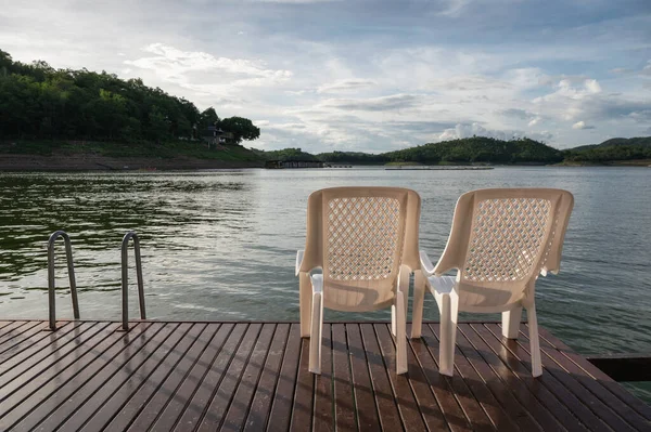 Two plastic chair on deck floating in lake at evening