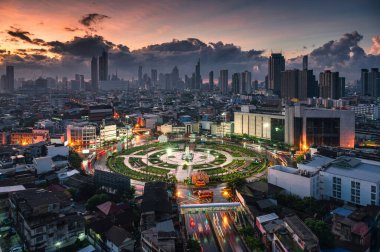 Bangkok, Tayland 'daki Wongwianyai kavşağının üzerinde araba trafiği ve gökdelenli bir anıt var.