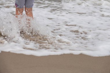 Yaz aylarında deniz suyu sahilde duran küçük kız