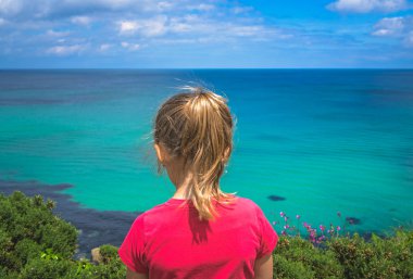 Kırmızı t-shirt ayakta küçük cliff ve Cornwall, İngiltere, İngiltere'de St. Ives yakınındaki Cornish kıyı şeridi çarpıcı admiting küçük kız giymiş