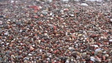 Küçük dalgalar renkli taş ve çakıl bir plajda yaz aylarında isabet