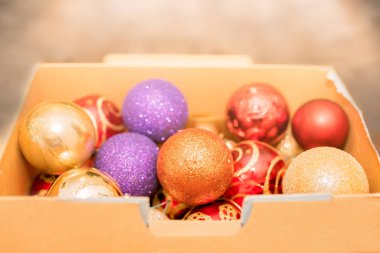 Bir karton kutunun içinde saklanan ve Aralık ayında Noel ağacı süslemek için kullanılan renkli Noel süslemeleri yakın çekim