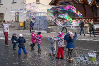 Karpacz, Polonya - Şubat 2018: Karpacz şehir, ana caddede dev sabun köpüğü yakalamaya çalışıyor çocuklar Kış Kayak Merkezi Lehçe