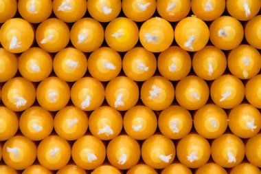 Bir dükkanda raflarda düzenlenmiş sarı parafin sopa mumlar