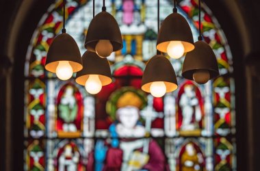 Victoria vitray kilise penceresi ön planda tavandan asılı lambalar ile