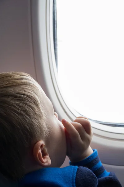 Little boy looking through the plane window before take off in the rain