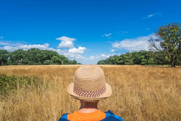 Kleiner Junge Mit Strohhut Steht Vor Einem Gelben Rasenfeld — Stockfoto