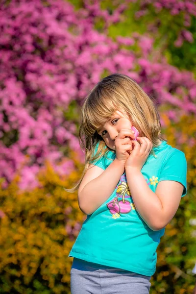 Küçük kız önünde renkli pembe ve sarı çiçek çiçekler baharda poz