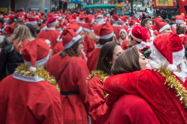 Лондон, Великобритания - Декабрь 2018: Мужчины и женщины, одетые в костюмы Санты, целуются и обнимаются, принимая участие в тематическом мероприятии SantaCon
