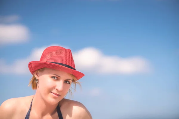 一个美丽的高加索妇女的肖像与红色柳条帽子在一个阳光明媚的日子在夏天 — 图库照片