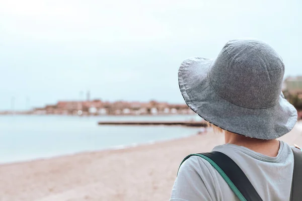 在黑山布德瓦的避暑胜地度假小镇 持蓝色帽子走在阳光明媚的海滨长廊上的白人妇女 — 图库照片