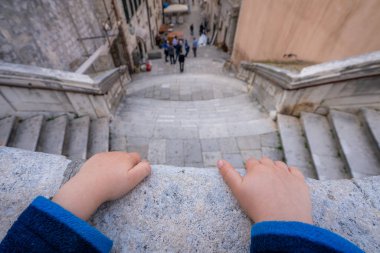 Dubrovnik, Hırvatistan - Nisan 2018: balkon korkuluk merdiven Dubrovnik Eski kentte yukarıda üzerinde tutan küçük bir çocuk el kapat