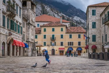 Kotor, Karadağ - Nisan 2018: Kotor Old Town tarihsel kare silah üzerinde sonra güvercin kovalayan çocuk,