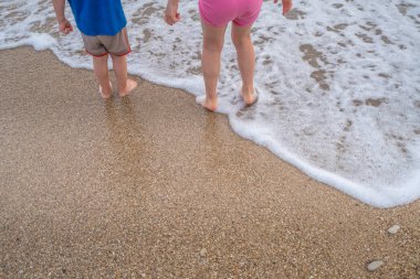 Küçük oğlan ve kız sahilde deniz sularında yaz aylarında ayakta