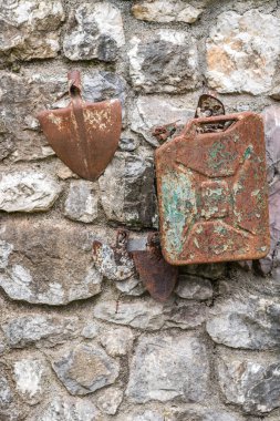 Eski paslı benzin bidonu ve kürek kafası kırsal kesimdeki bir binanın duvarına yapışmış.