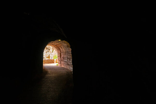 Dark tunnel cut out in the seaside rocky cliffs on the walking path in Petrovac bay, on the coast in Montenegro