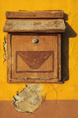 İspanyol evinin sarı duvarında eski ahşap bir posta kutusu.