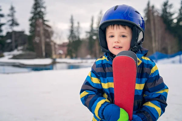 Kleine jongen houdt zijn ski's in de winter — Stockfoto