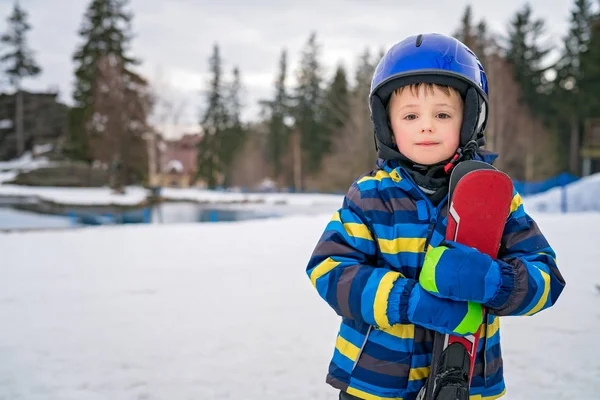 Kleine jongen houdt zijn ski's in de winter — Stockfoto