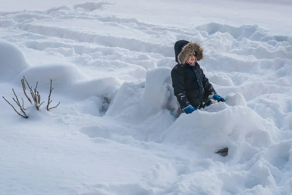 Ragazzino seduto in una neve profonda — Foto Stock