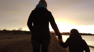 Anne ve oğlu birlikte el ele tutuşarak ve Zante Adası'nda alacakaranlıkta yaz aylarında Tsilivi Plajı batan doğru yürüyüş, Yunanistan