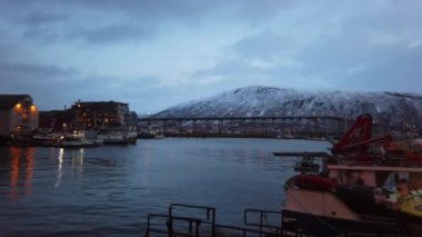 Arka planda Tromsoysundet Boğazı'nın karşısındaki ünlü Tromso Köprüsü ile liman ve liman, Kuzey Norveç
