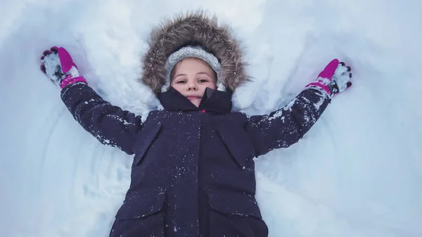 Ένα κοριτσάκι ξαπλωμένη σε ένα βαθύ χιόνι — Φωτογραφία Αρχείου