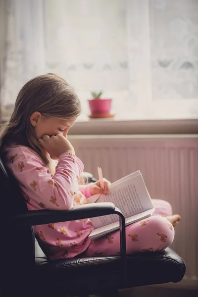 Chica en pijama leyendo un libro —  Fotos de Stock