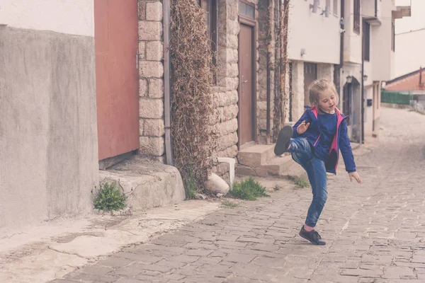 Bambina che pratica calci su una strada — Foto Stock