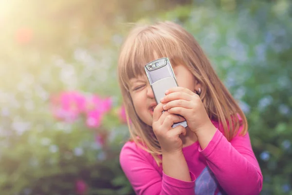 Bonita menina brincando com o telefone celular — Fotografia de Stock