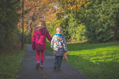 Parkta el ele yürüyen kardeşler