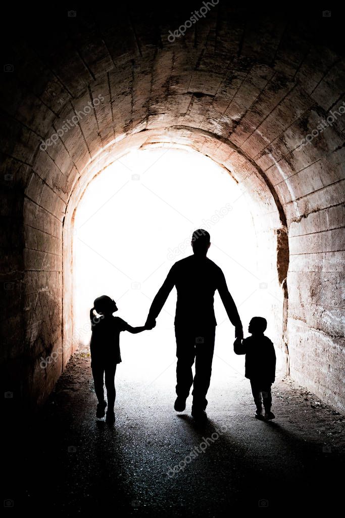 Father walking with his two children in a tunnel