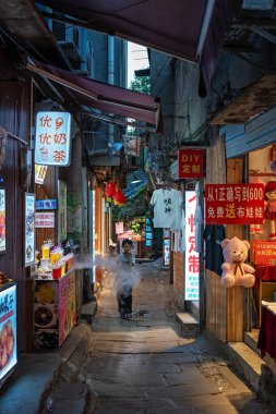 Chongqing, Çin - Ağustos 2019 Gıda tezgahları ve hediyelik eşya dükkanları arasında dar bir geçitte koşan küçük çocuk, Ci Qi Kou Antik Kasabası