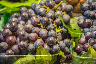 Çin 'de satılık taze ve lezzetli koyu kırmızı üzümler yığını.