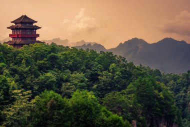 Tianzi dağ sırasının baş döndürücü kaya sütunlarına bakan bir dağın tepesinde geleneksel Çin mimari tapınağı binası Avatar dağları doğa parkı, Zhangjiajie, Çin