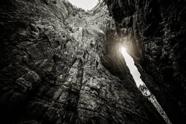 Uzunshuixia Fissure Ulusal Parkı, Wulong Bölgesi, Chongqing, Çin 'in doğal kayalık ve karst arazisinde parlayan güneşin siyah ve beyaz görüntüsü.