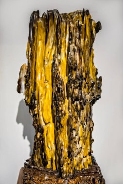 Garip görünümlü sarımsı kahverengi dikey mineral taşı bir müzede sergileniyor.