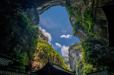 Çin 'deki Wulong Ulusal Parkı' nın karst kayalık manzarası arasında taş kemerin önündeki geleneksel Çin mimari yapıları.