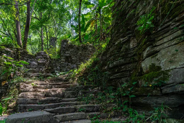 A pathway of concrete steps among old abandoned houses of an old village located in the middle of the lush tropical forest near Yangshuo, China