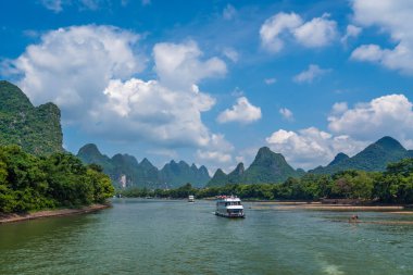 Yangshuo, Çin - Ağustos 2019: Guilin ve Yangshuo kasabaları arasındaki görkemli Li nehri üzerindeki karst dağ manzarasında turist taşıyan gezi teknesi