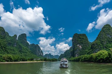 Yangshuo, Çin - Ağustos 2019: Guilin ve Yangshuo kasabaları arasındaki görkemli Li nehri üzerindeki karst dağ manzarasında turist taşıyan gezi teknesi