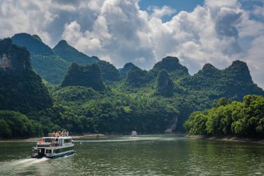 Yangshuo, Çin - Ağustos 2019: Guilin ve Yangshuo kasabaları arasındaki görkemli Li nehri üzerindeki karst dağ manzarasında turist taşıyan gezi teknesi