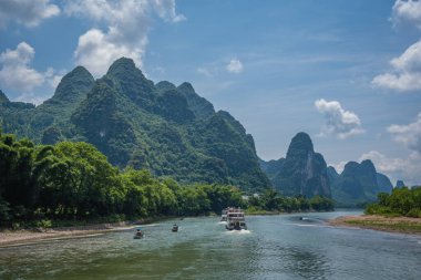 Yangshuo, Çin - Ağustos 2019: Guilin ve Yangshuo kasabaları arasındaki görkemli Li nehri üzerindeki karst dağ manzarasında turist taşıyan iki gezi teknesi