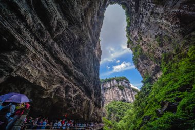 Wulong, Çin - Ağustos 2019: Wulong Ulusal Parkı 'nın karst arazisi arasında bir kanyonda doğal kayalık yarığına doğru dar bir yolda yürüyen turist kalabalığı