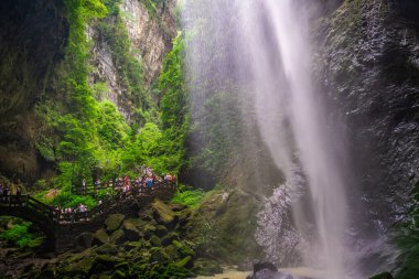 Wulong, Çin - Ağustos 2019: Büyük Şelale 'nin altında Wulong bölgesindeki Wulong Fissure Ulusal Parkı' ndaki bir vadi vadisinde dar bir yolda yürüyen turist kalabalığı