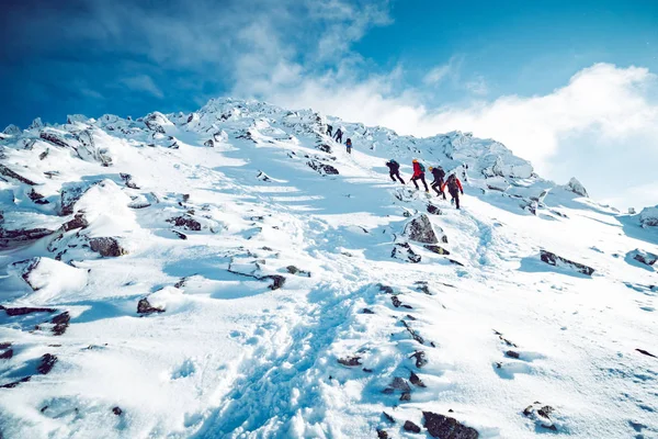 Um grupo de alpinistas ascendendo uma montanha no inverno — Fotografia de Stock